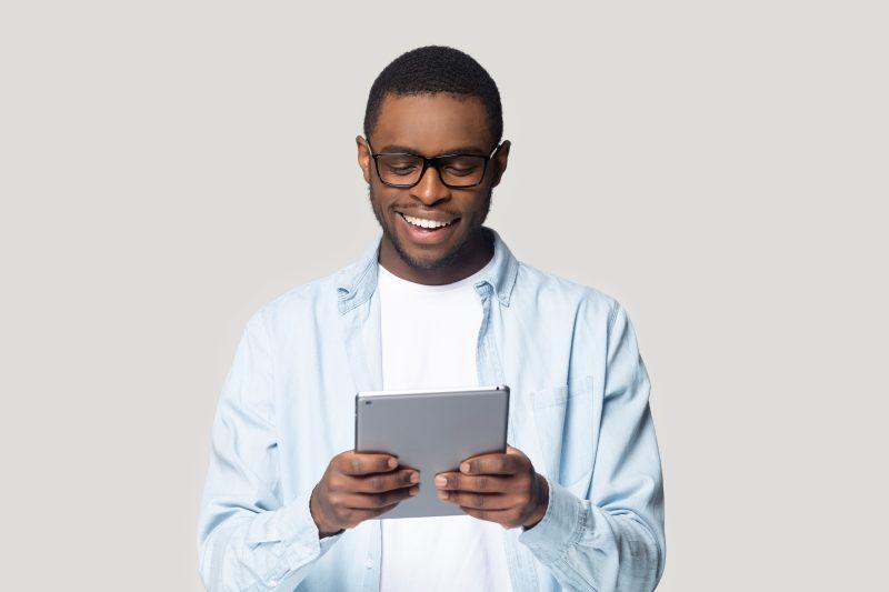 Jeune homme noir avec des lunettes tenant une tablette.