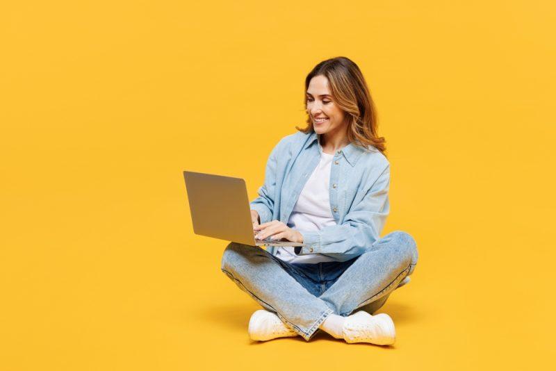 Femme entrepreneure souriante travaillant sur son ordinateur portable pour découvrir comment gagner de l'argent avec l'IA