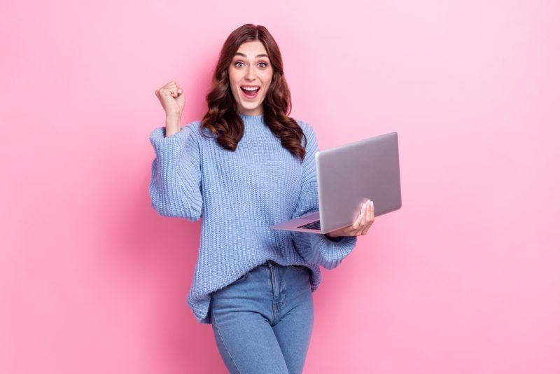 Entrepreneuse souriante utilisant un ordinateur portable après une formation communication digitale avec CréActifs