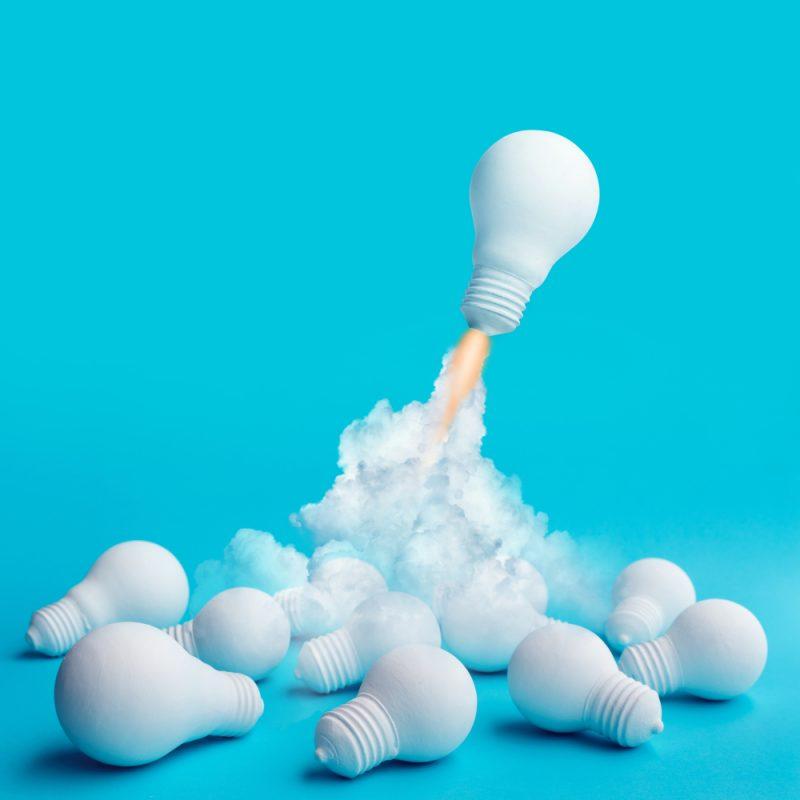 Ampoule qui décolle comme une fusée sur fond bleu pour illustrer une formation création d’entreprise chez CréActifs